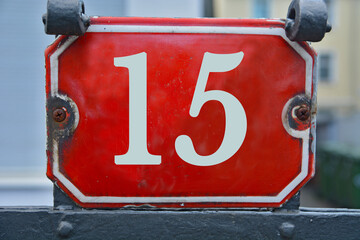 A red number plaque, showing the number fifteen, 15
