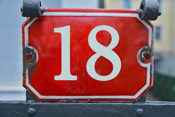 A red number plaque, showing the number eighteen, 18