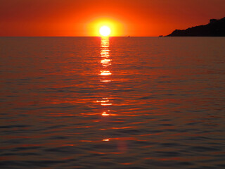 Obraz premium Bright sunset over the sea. The sun on the horizon is reflected on the surface of the water