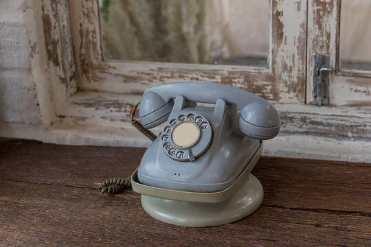 Retro rotary telephone on wood table. Vintage telephone. grey old phone. Retro telephone on table in front windows background.
