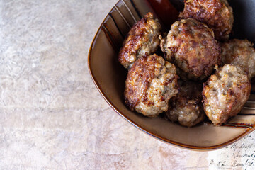 Meatballs lie in a clay plate on a vintage beige background, space for text
