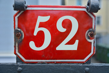 A red number plaque, showing the number fifty-two, 52