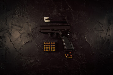 Pistol and bullets on concrete table. Top view of neatly arranged cartridges and gun. Weapons of defense or attack. Automatic firearms. Flat lay with copy space.