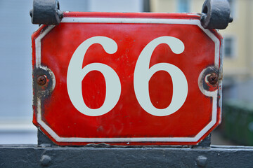 A red number plaque, showing the number sixty-six, 66