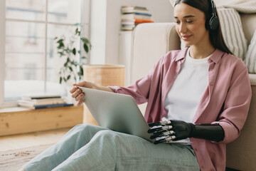 Close-up picture of young charming female in casual clothes with prosthesis arm watching movie or...