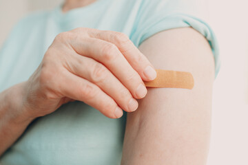 Vaccination elderly woman in doctor office with adhesive covid-19 vaccine plaster