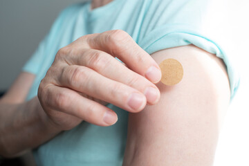 Vaccination elderly woman in doctor office with adhesive covid-19 vaccine plaster