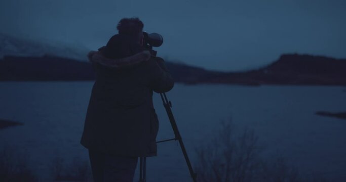 Man looking through binoculars bird watching at lakeside