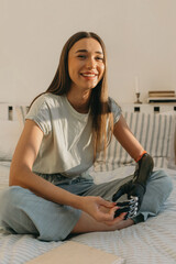 Indoor portrait of beautiful laughing female with artificial black metal hand sitting on bed in...