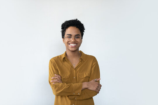 Cheerful confident African businesswoman wearing eyeglasses, posing with folded arms, looking at camera with toothy smile. Millennial female customer, young woman headshot portrait isolated on white