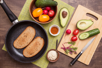 Cooking vegan vegetarian sandwiches, toasts with different vegetables and toasts of fried bread on kitchen. Healthy diet food concept	
