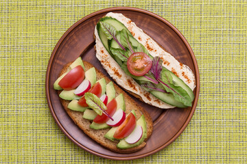 Vegan, vegetarian toasts, bruschetta with different vegetables, avocado, tomato, hummus, cucumber, radish and greens close up