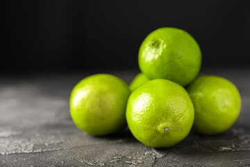 Lime, juicy ripe citrus fruits on a dark background. Ingredients for preparing refreshing drinks and cocktails. Mojito. Selective focus, top view and copy space