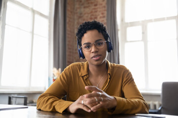 Confident African student, worker, intern in headphones head shot portrait. Friendly young Black...