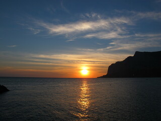 Beautiful sunset on the sea, mountain silhouette and orange sun on the horizon, Crimea, Black Sea