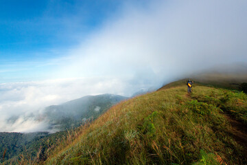 Photographer walking in white mist or foggy on the small road on the mountain.