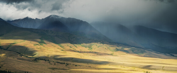 Thunderclouds over a mountain valley, contrasting light