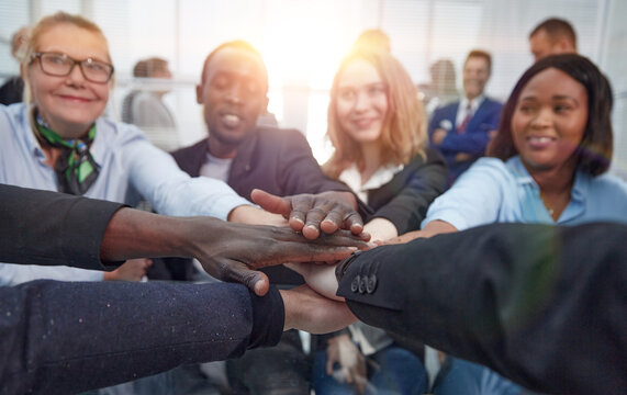 group of diverse employees joining their palms over the desktop.