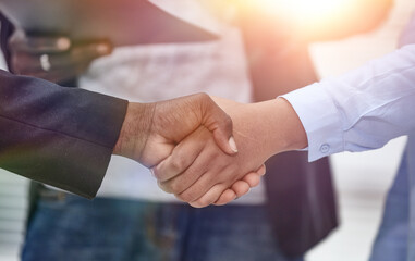 Closeup of handshake of business partners on background of emplo