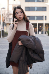 Portrait of a young asian woman talking on her smartphone in the street.