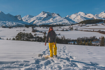 A full-body shot of a young Caucasian woman playing with snow in the French Alps mountains (La Joue du Loup, Devoluy)