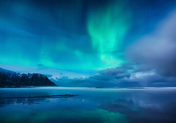 Aurora Borealis. Skagsanden beach on Lofoten Islands, Norway. Northern light. Reflections on the water surface.