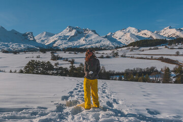 A full-body shot of a young Caucasian woman playing with snow in the French Alps mountains (La Joue...