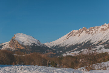 Fototapeta premium A picturesque landscape view of the snowcapped French Alps mountains with a hiking path in the snow on a cold winter day (La Joue du Loup, Devoluy)