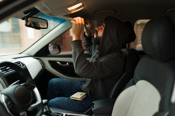Thief looking for valuable things on a car
