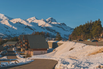 A picturesque landscape view of the snowcapped French Alps mountains and the ski resort buildings on a cold winter day (La Joue du Loup, Devoluy)