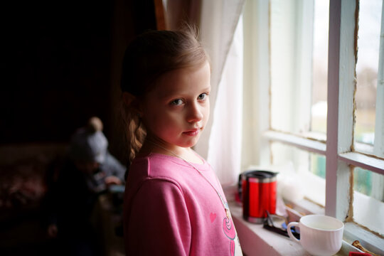 Girl in a village house looking out the window. High quality photo