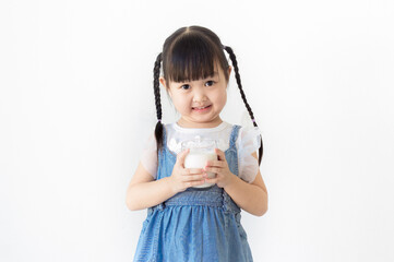 Portrait cute smiling Asian girl holding a glass of milk with white background..