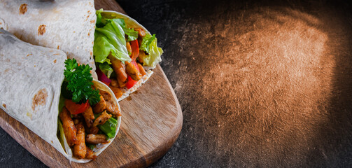 Tortilla with chicken and fresh vegetables on a cutting board
