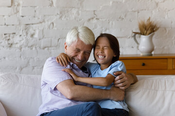 Happy cheerful granddad cuddling, tickling excited laughing grandkid boy. Grandson and grandpa...