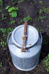 large vertical photo. summer time. aluminum jar in the middle of the garden. environmentally friendly materials on the farm. view from above. metal lock with a clip on the barrel.