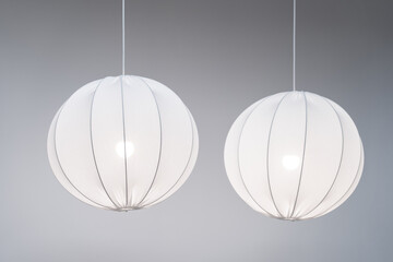 Two white modern pendant lamps, fabric spherical chandeliers in Scandinavian style on grey...