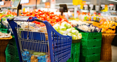 A shopping cart with grocery products in a supermarket