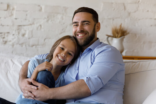 Cheerful loving father embracing adopted pre teen son with care, tenderness, looking at camera, smiling, Dad hugging kid on couch, enjoying happy fatherhood. Family head shot portrait - Powered by Adobe