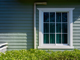 A white house window with glass, green curtain decoration on the small light green wooden resident with copy space, view from outdoor. - Powered by Adobe