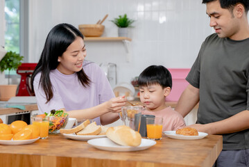 happy family together. Asian parent eating breakfast with little son in the kitchen.