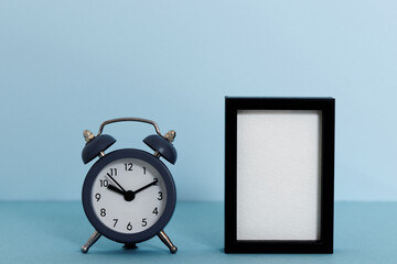 Blue alarm clock on bright background and frame with blank copy space. Ten past ten time hour.