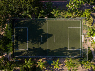 Aerial view of the soccer field. Top view. Sunset. Green synthetic grass and railings around