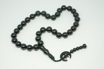 Black prayer beads for worship and dhikr of Muslims on a white background.