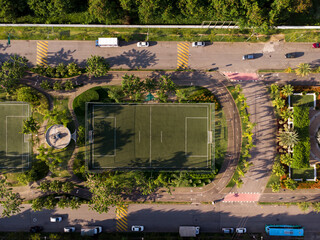 Aerial view of the soccer field. Top view. Sunset. Green synthetic grass and railings around