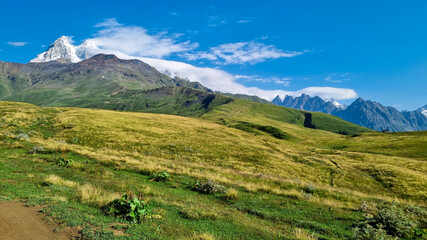 Panoramic view on the Ushba mountain peaks covered by clouds near Mestia in the Greater Caucasus Mountain Range, Upper Svaneti, Country of Georgia. Hiking trail to the Koruldi Lakes. Wanderlust.