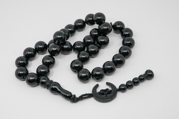 Black prayer beads for worship and dhikr of Muslims on a white background.