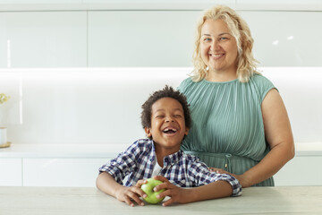 Fototapeta premium Happy mother and child boy laughing and holding green apple fruit. Happy family.