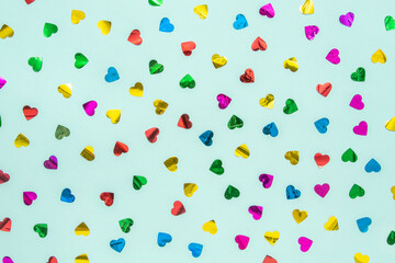 Hearts in red, yellow, beach, green and purple are better on a turquoise blue and green background. Minimal concept of Valentine's Day. Scattered love.