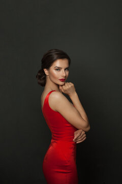 Portrait of young smiling woman with bright impressive red lips. Studio photo shoot of pretty woman in fashionable red dress