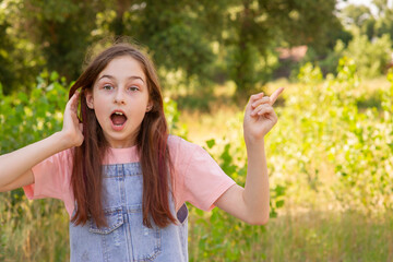 The surprised face of a child. Girl 11 years old against the background of foliage in the season.
